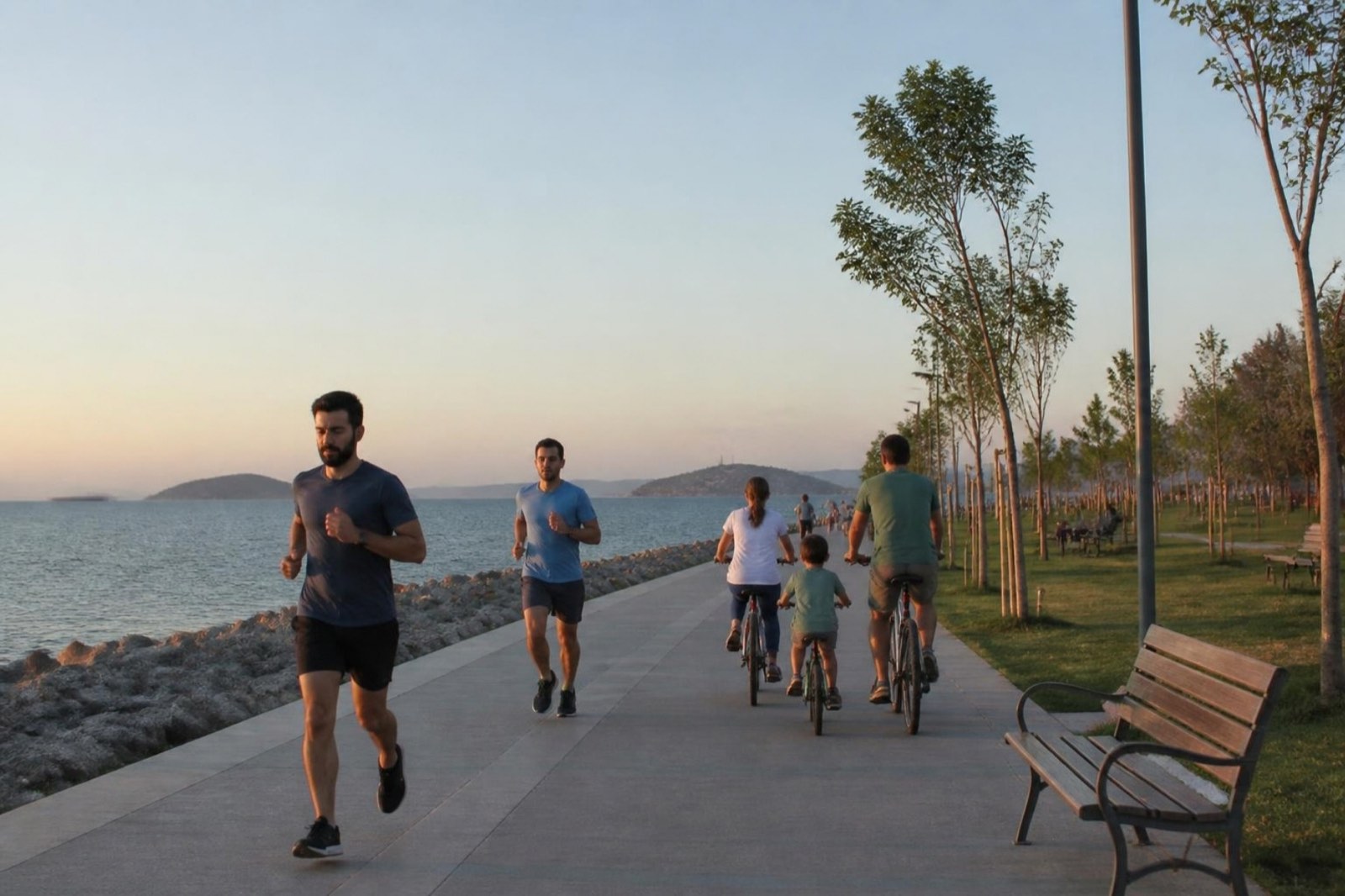 Runners and a family cycling on a seaside promenade at sunset