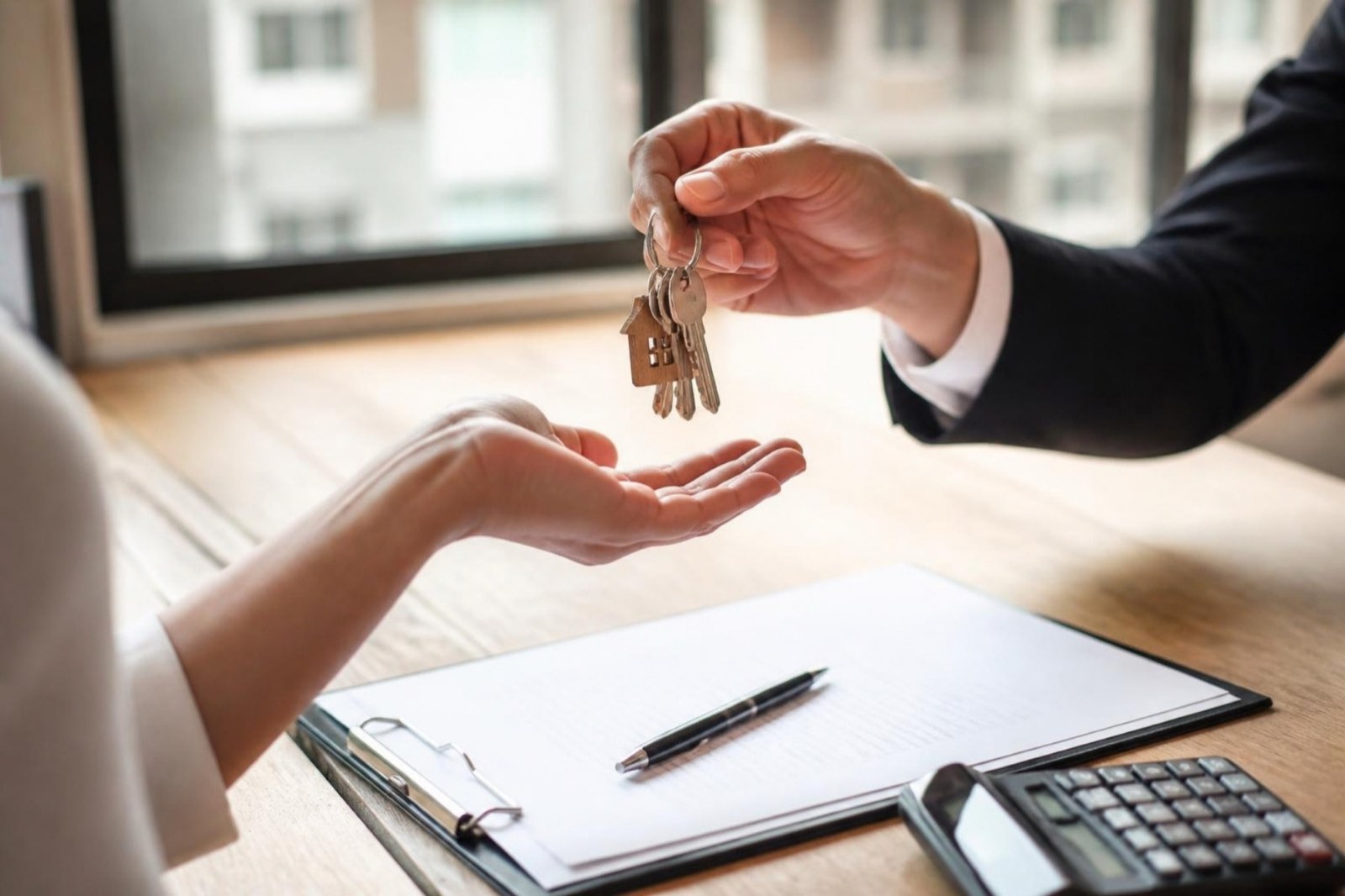 Apartment keys being handed over across a table with documents