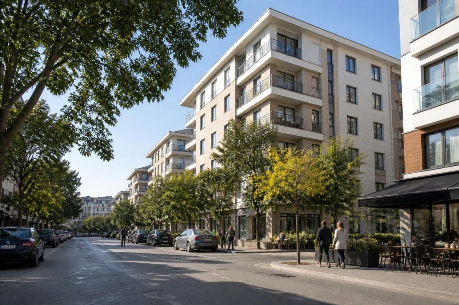 Tree-lined residential street with mid-rise apartment buildings and a corner café