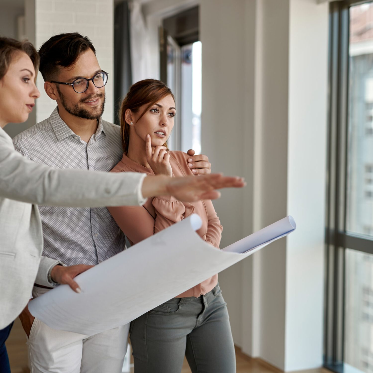 Young couple analyzing housing project while buying a new apartment.